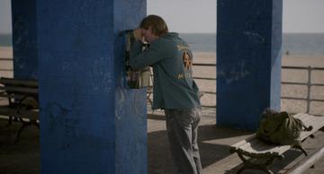 Caught Stealing_Hank makes a call from the beach